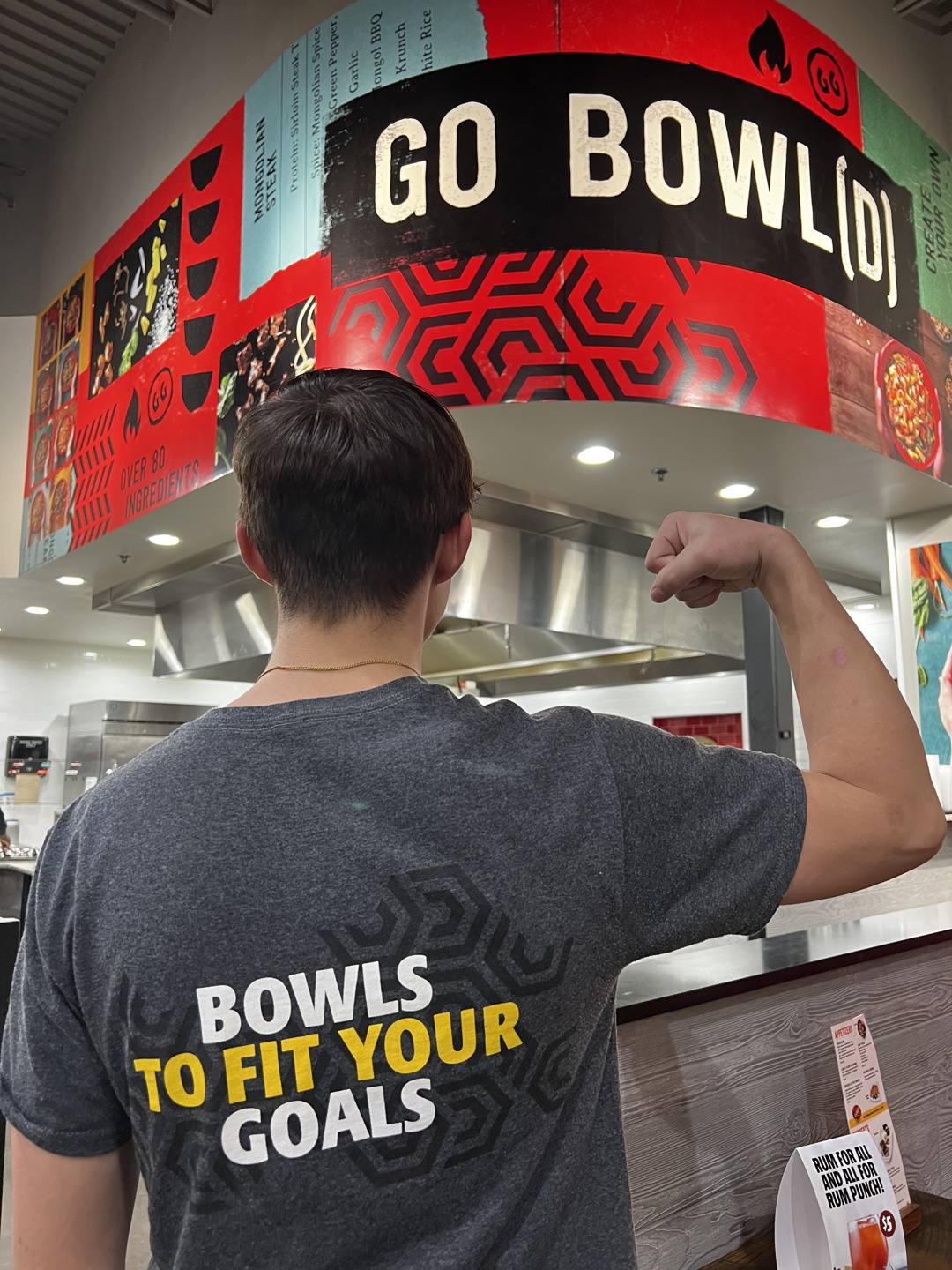 A Genghis Grill team member in a Bowls to Fit Your Goals tee at the counter